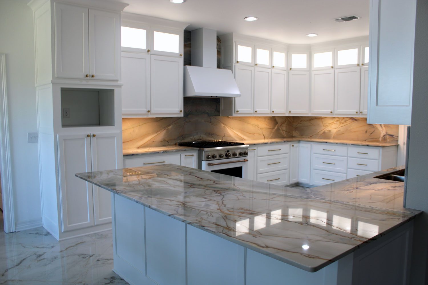 A remodeled kitchen with white cabinetry and marble counters by Custom Wordworks