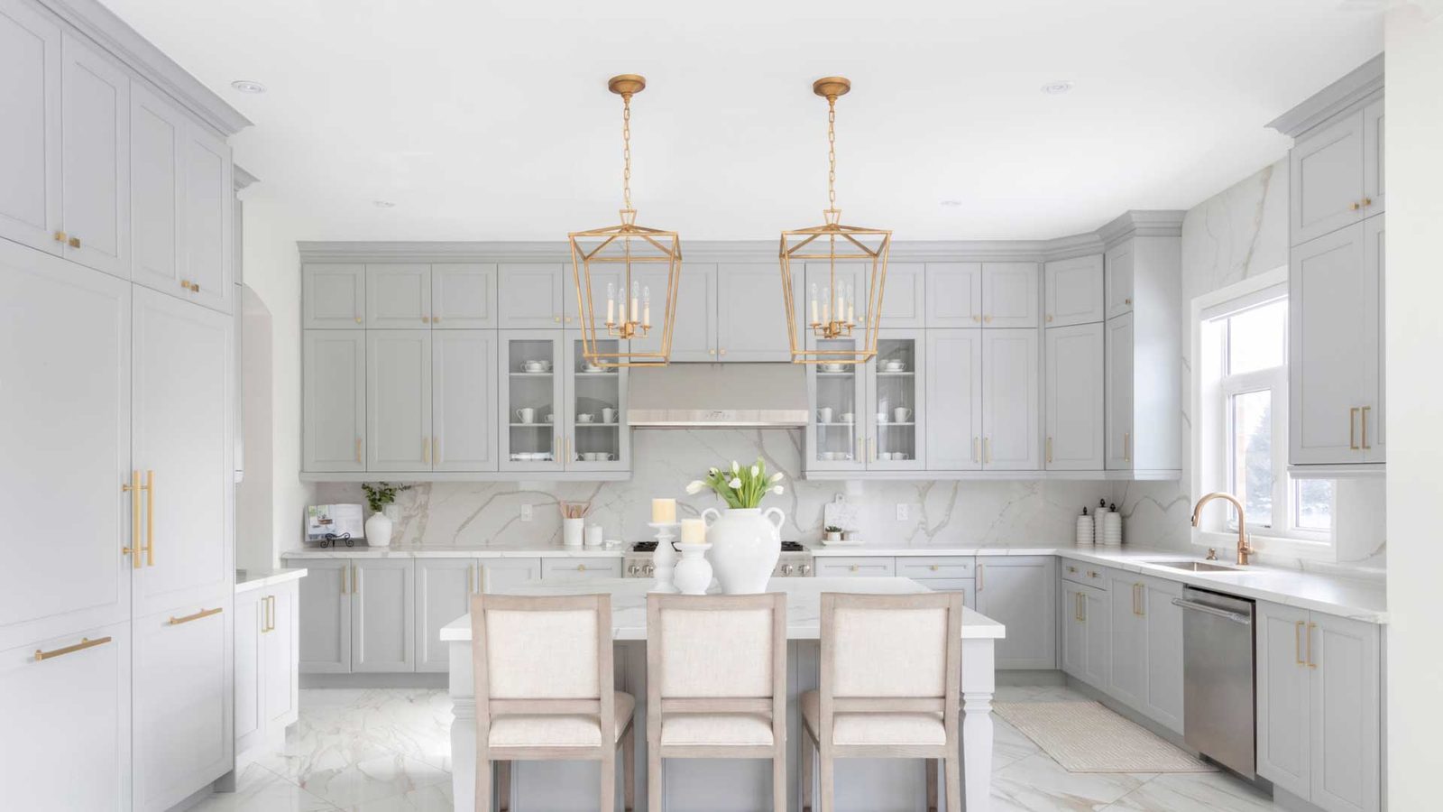 A custom white kitchen with glass-front cabinetry and pendant lighting, built by Custom Wordworks